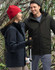 A unisex quilted waterproof jacket in navy and black, displayed by a man and woman in a forest setting.