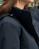 A unisex quilted waterproof jacket in navy blue, featuring a zip and adjustable hood, with a branding logo visible.
