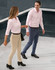 A pair of flexi chino pants in beige and navy, worn by a man and woman walking together in a modern setting.