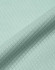 A close-up of a light mint green jacquard knit fabric with a textured pattern. The material appears soft and sustainable.