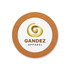 A circular cork coaster featuring a white centre with a gold logo and brown text.