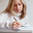A bamboo pen is being held by a person who is writing in a notebook.