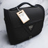 A black luggage tag made from bamboo, attached to a textured black travel bag with a handle.