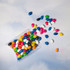 Assorted mini jelly beans in various colours, including black, white, blue, green, pink, orange, and yellow, in a pillow pack.