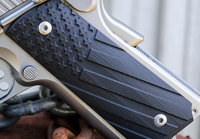 Close-up of a textured black handgun grip with diagonal grooves and metal frame details visible.