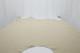 Picture of Vintage White, soft white colored leather hide for upholstery displayed on a table.