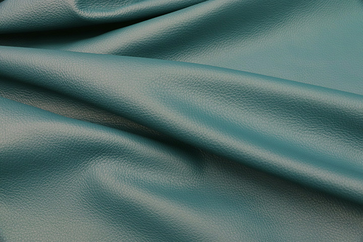 Close-up picture of Teal, rich blue green full grain leather for upholstery with pebble grain texture