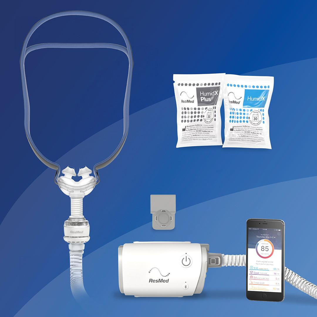Resmed AirMini - P10 Starter kit, including the portable CPAP device, a flexible hose, two HumidX Plus and HumidX moisture absorption packets, a power supply, and a smartphone displaying the SleepScore app for sleep tracking.