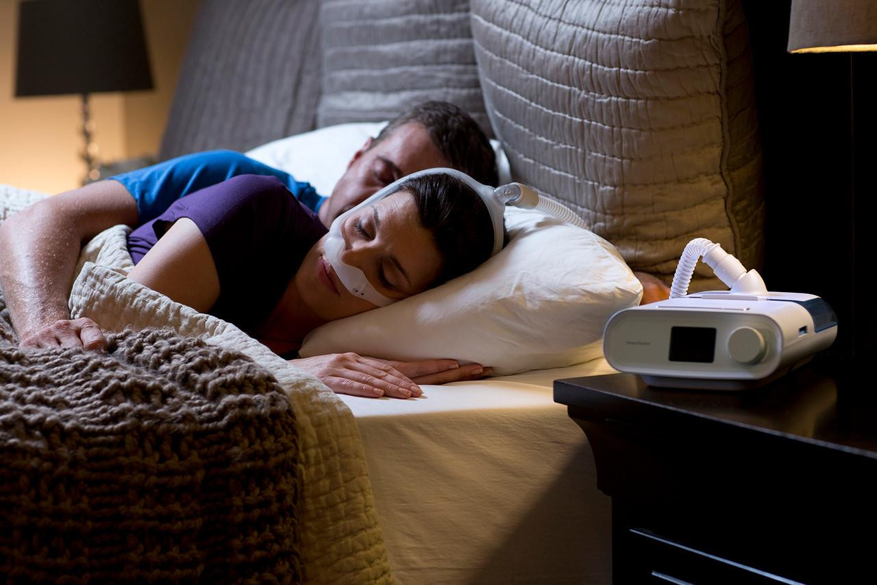 Philips Respironics Philips DreamStation Pro Mask CPAP Package, a CPAP machine with mask and tubing helping a woman sleep peacefully during the night.