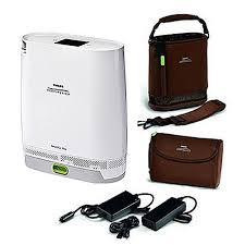 Philips Respironics Simply Go Mini Oxygen Concentrator with standard battery, compact portable device with accessories including carrying case, power cords, and battery pack.