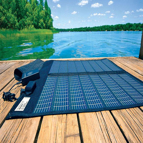Transcend Solar Panel, portable solar panel placed on a wooden dock by a lake with green trees and blue sky in the background.