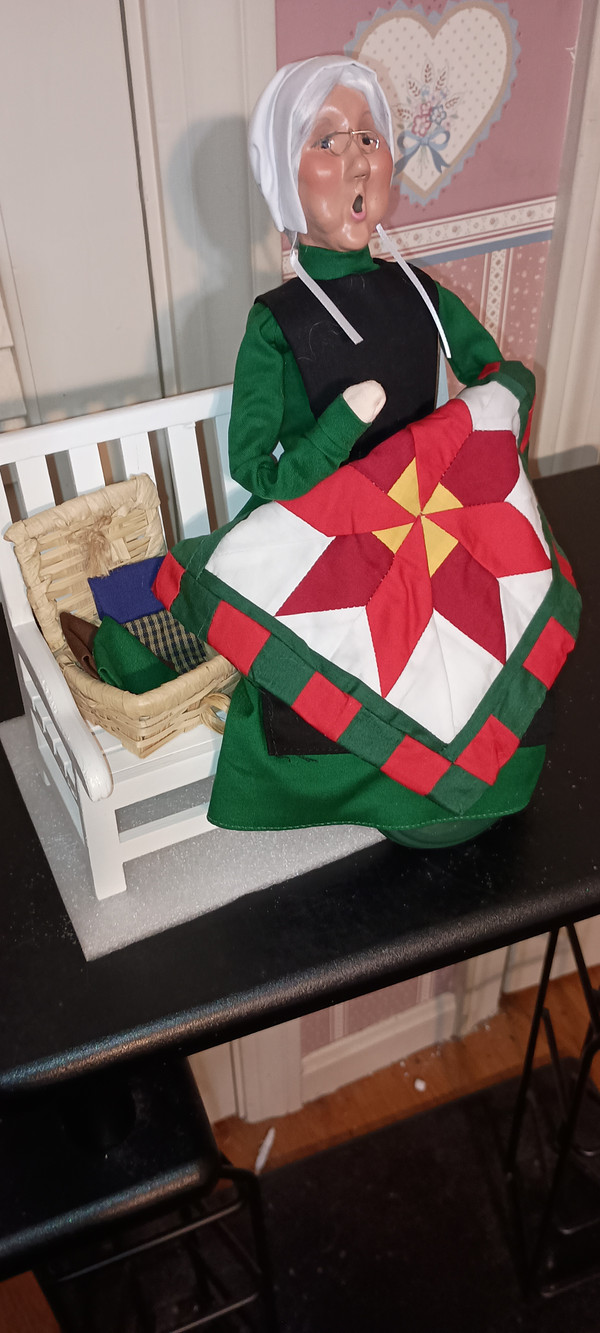 BYERS CHOICE CAROLER-2025- AMISH GRANDMOTHER ON BENCH-NEW