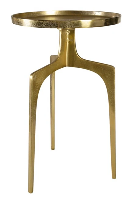 Providing an organic global feel, this cast aluminum accent table features a shapely curved base and round top, finished in a textured soft gold.