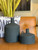 A crusty black reactive glaze provides stark contrast to the flat-bottomed contemporary vases. Each sports a whimsical curled handle.