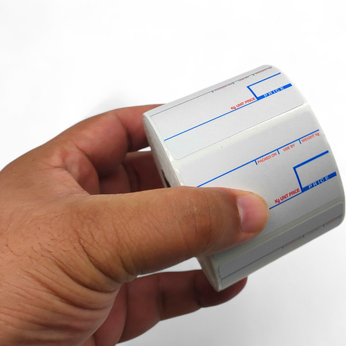 Hand holding a small white thermal till roll with blue and red printed guide lines.
