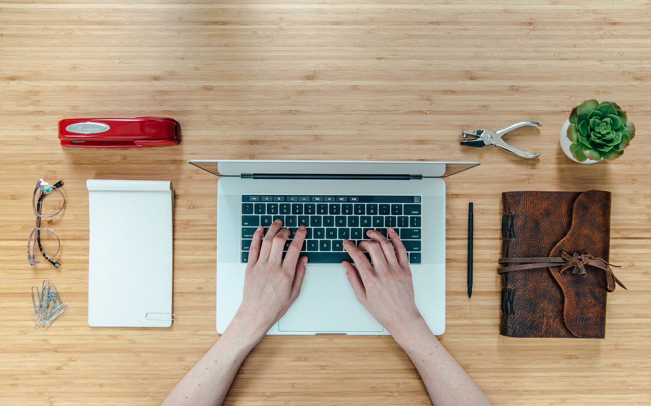 A desk with paperwork, a laptop and stationery seen from above