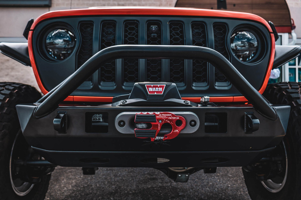 Poison Spyder Front JL/JT BRUISER Bumper in black, featuring a robust design with a central winch mount, surrounded by a sturdy frame and integrated fog light openings.