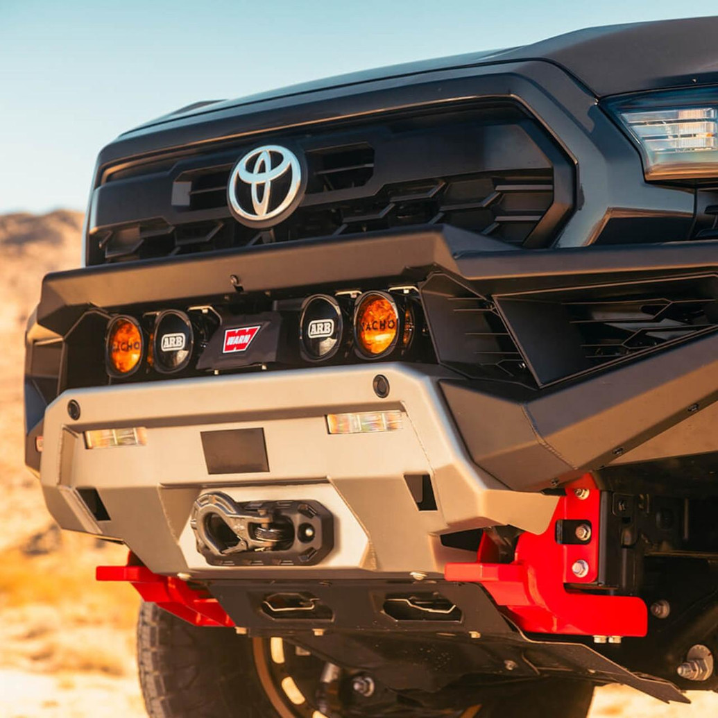 ARB Zenith Winch Bumper for Toyota Tacoma (2024+), black and silver off-road bumper with built-in winch and floodlights mounted on the front grille.