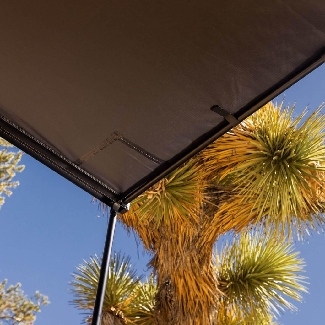 ARB Hard Case Awning with Light, outdoor canopy with integrated LED light and sturdy hard case in a desert setting with a palm tree.