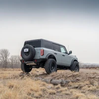 ARB Rear Zenith Bumper 5680020B, black off-road rear bumper mounted on a gray Ford Bronco with a spare tire, shown from a rear three-quarter angle on rocky terrain.