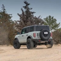 ARB Rear Zenith Bumper 5680020B, black off-road rear bumper installed on a Ford Bronco with a spare tire, shown from the rear three-quarter view on a dirt trail