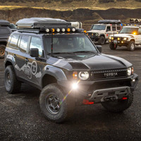 Old Man Emu BP-51 Kit FR 3 in/0-330 lb, RR 2 in/0 lb 2217K, adjustable off-road vehicle suspension kit installed on a rugged Toyota SUV with other off-road vehicles in the background.