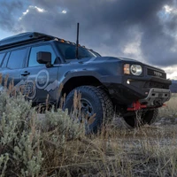 Old Man Emu BP-51 Kit FR 3 in/0-330 lb, RR 2 in/440 lb 2218K, off-road vehicle suspension upgrade installed on a black SUV, rugged outdoor landscape with clouds in the sky.