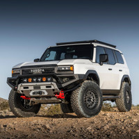 Old Man Emu MT64 Kit FR 3in/220-330lbs, RR 2in/0lb 2124K, image of a lifted Toyota off-road vehicle with large tires and rugged design amid desert terrain.