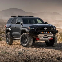 Old Man Emu MT64 Kit FR 3 in/0 lb, RR 2 in/0 lb 2134K, a rugged Toyota off-road vehicle with large tires, black grille, and additional front bumper lights, driving across a rocky desert landscape.