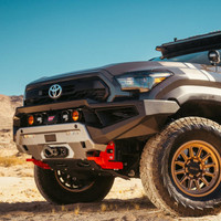 ARB Zenith Winch Bumper for Toyota Tacoma (2024+), rugged black and silver off-road vehicle front bumper with winch, auxiliary lights, and heavy-duty construction in desert landscape.
