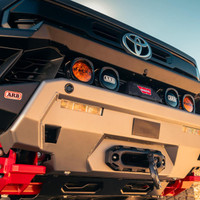 ARB Zenith Winch Bumper for Toyota Tacoma (2024+), close-up of the rugged black and silver front bumper equipped with multiple ARB and Warn logos, integrated fog lights, and a mounted winch system.