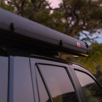 ARB Hard Case Awning with Light, mounted on top of a vehicle, outdoor setting with trees in the background.