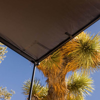 ARB Hard Case Awning with Light, outdoor canopy with integrated LED light and sturdy hard case in a desert setting with a palm tree.
