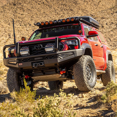 ARB Summit MKII Winch Bumper for Toyota Tacoma (2024+), rugged off-road truck with heavy-duty bumper, auxiliary lights, and roof storage on desert terrain.