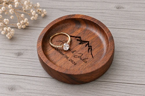 Personalized round walnut ring dish featuring custom engraved names, wedding date, and mountain design. Handcrafted from natural walnut wood, this engraved wooden ring tray holds wedding bands and engagement rings. A beautiful keepsake for wedding ceremonies, anniversaries, proposals, and personalized gifts for couples.