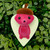 A red creature wearing a brown acorn hat emerging from a mint green leaf