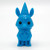 A solid blue figurine of an animals wearing a hat and cape