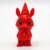 A solid red figurine of an animal wearing a hat and cape