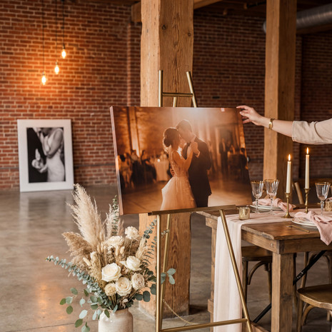 Wedding photo canvas print displayed on a gold easel at a reception venue with floral arrangements and table settings