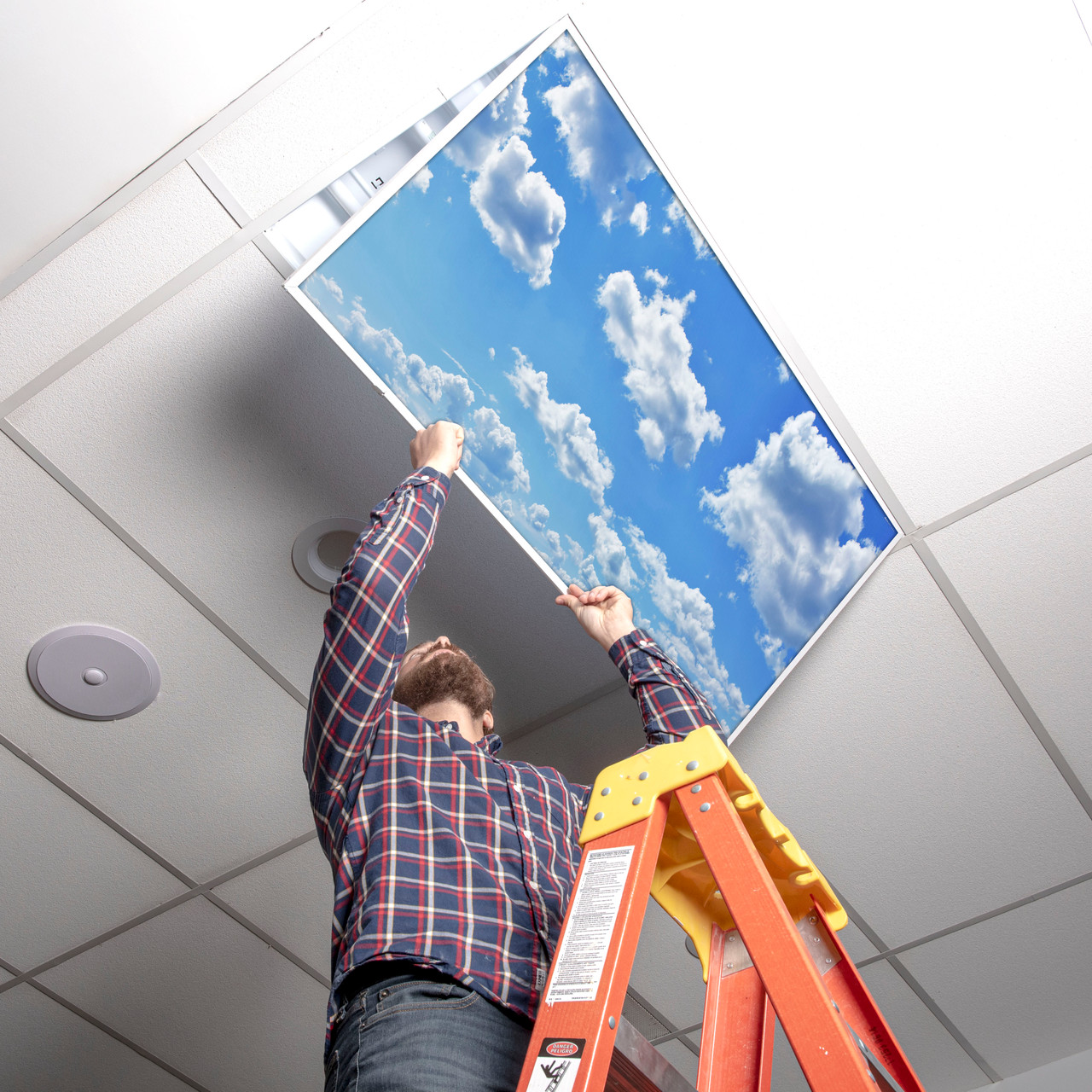 Installer placing a cloud fluorescent light cover into a 2x4 ceiling troffer
