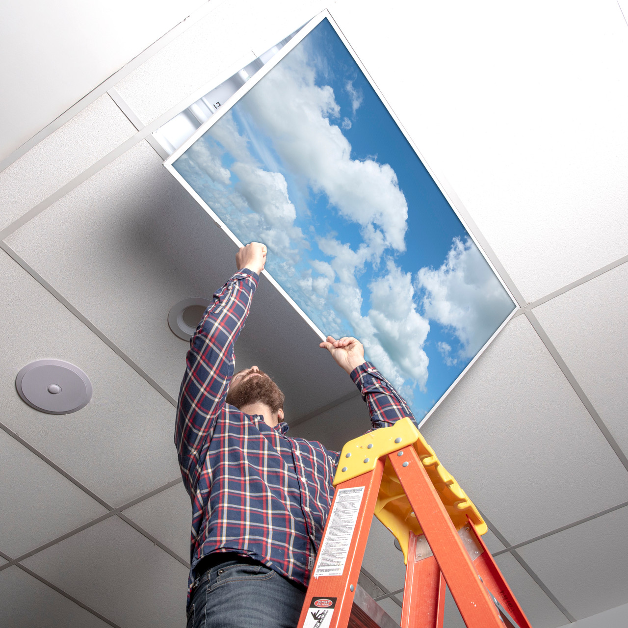 Installer laying a cloud light cover into a 2x4 fluorescent fixture