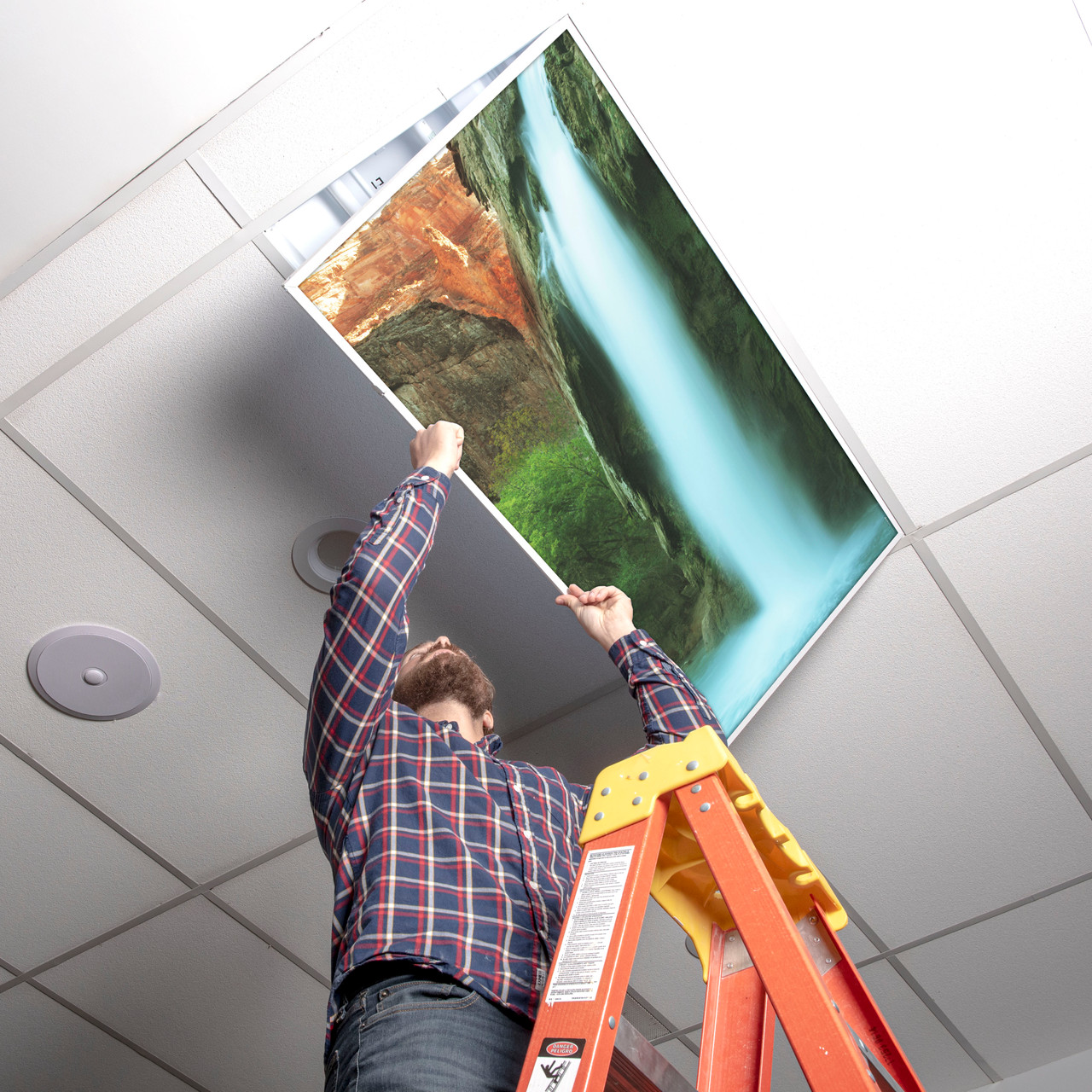 Installer placing a waterfall light cover into a ceiling troffer