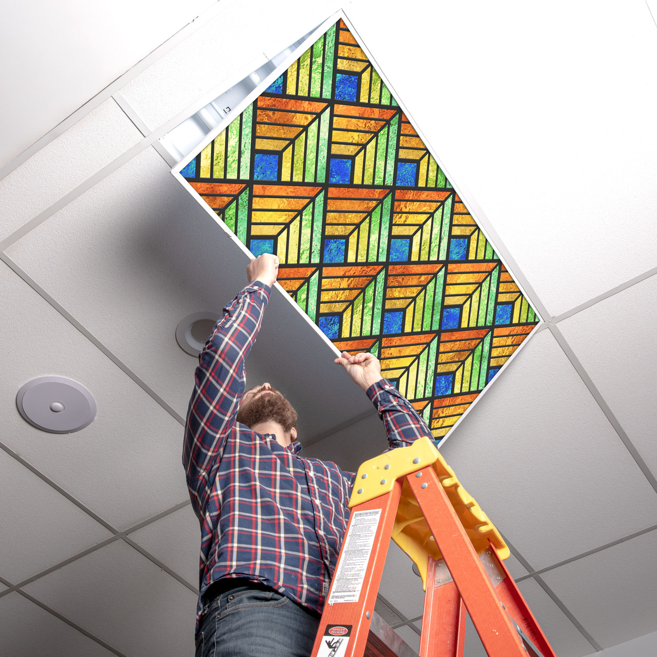 Installer placing a stained glass light cover into a 2x4 ceiling fixture