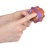 Hand poking the bubble popper ball against a white background.