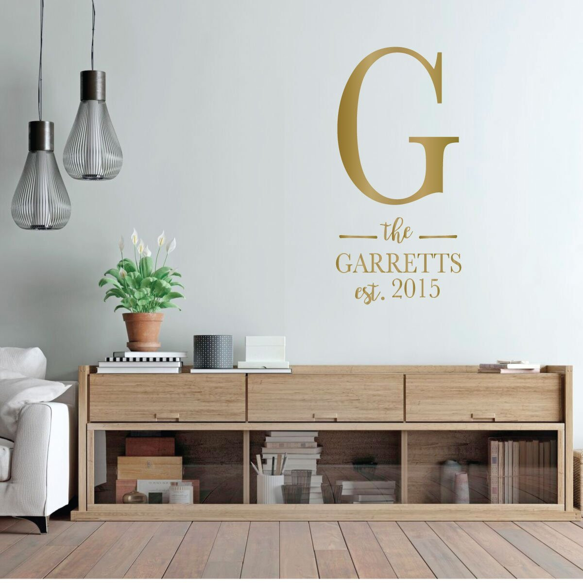 Personalized family name wall decal The Garretts Est 2015 in metallic gold on a modern living room wall