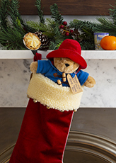 Paddington Bear hanging in a Christmas stocking on a fireplace