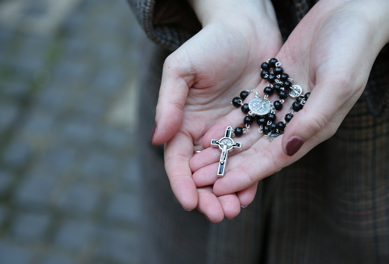 A rosary held in a cupped hand
