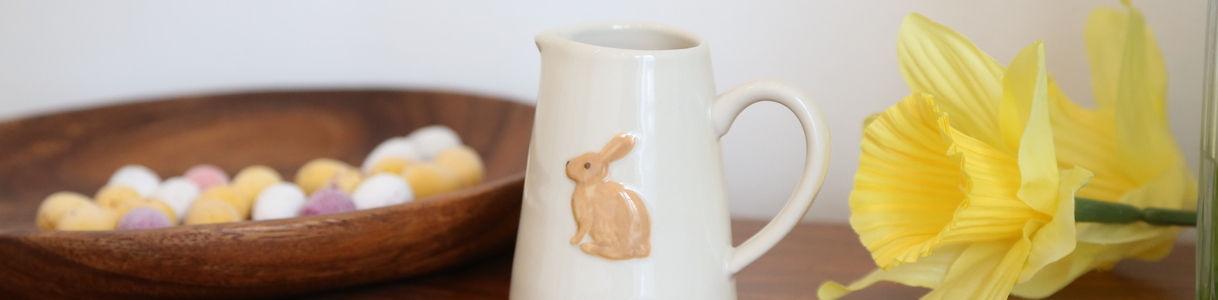 A stoneware jug featuring a rabbit surrounded by a daffodil and mini chocolate eggs