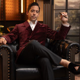 Michael Knowles wearing the Mayflower Smoking Jacket in color Mayflower Dawn Maroon while seated and enjoying a Mayflower Dawn cigar