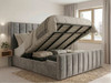 A grey velvet ottoman bed with the mattress platform lifted open by a gas-lift mechanism, revealing a spacious under-bed storage compartment with solid base boards